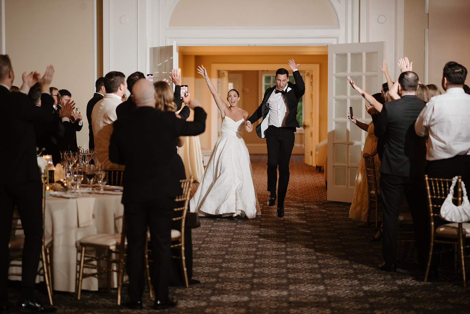 Newlyweds cheering and jumping with excitement during their high-energy reception grand entrance.